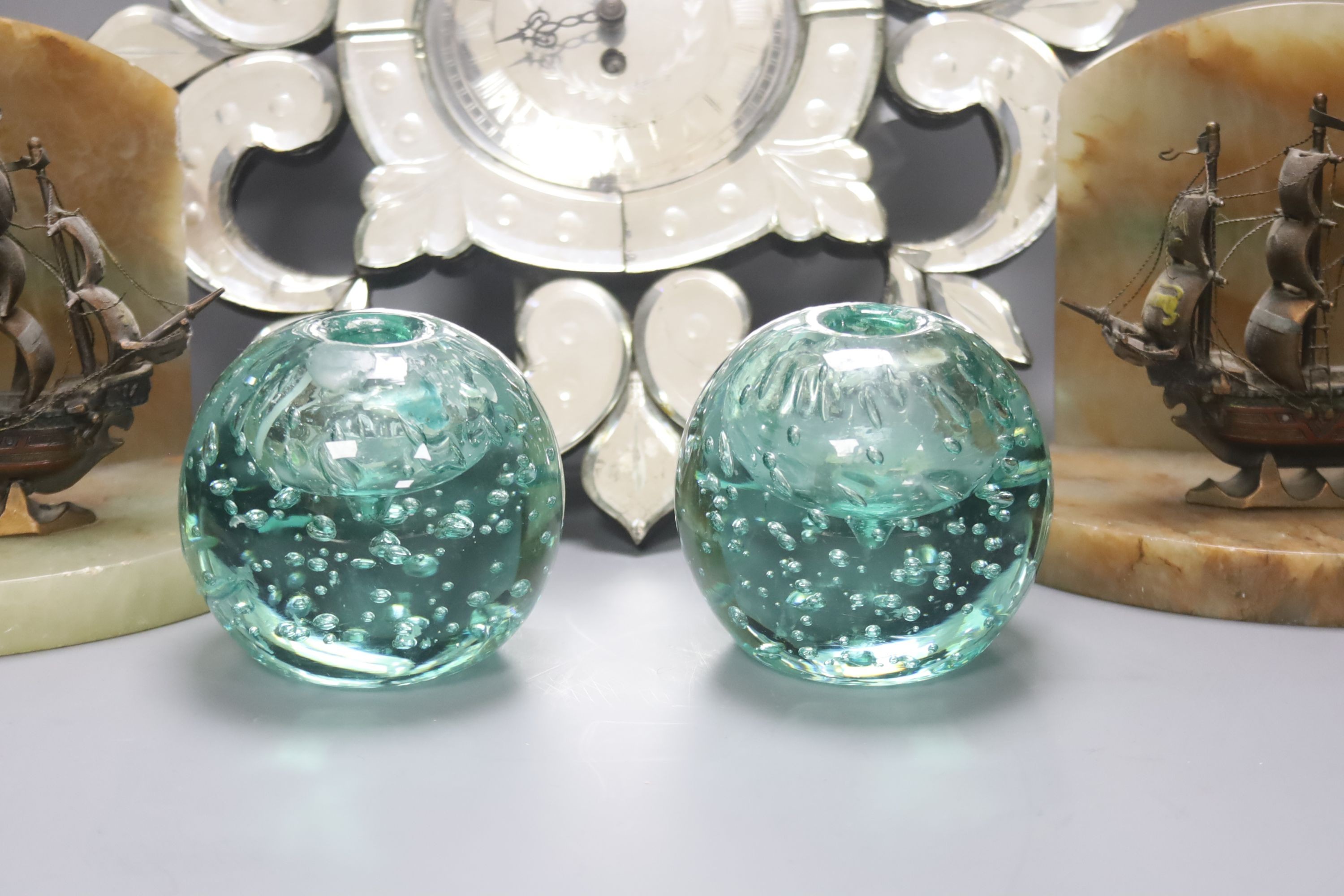A small Venetian mirrored glass wall clock and a pair of green glass ‘candleholder’ dumps and a pair of ship bookends 33cm